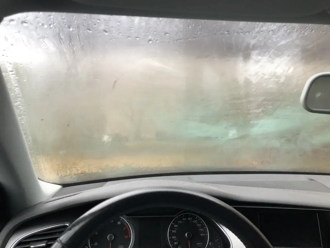 Vista desde el interior de un coche con el parabrisas empa&ntilde;ado, dificultando la visibilidad exterior. Es hora de desempa&ntilde;ar cristales coche.