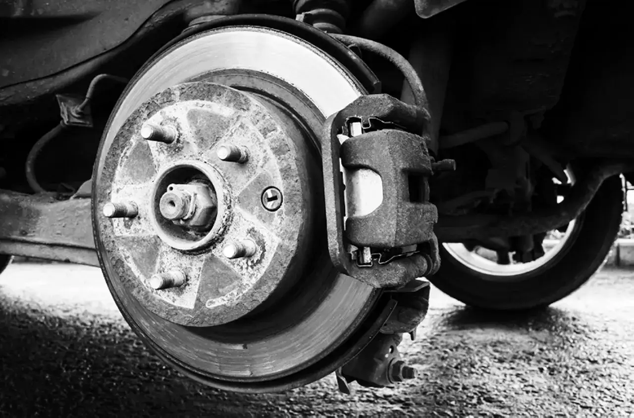 Primer plano de un disco de freno y pinza de un coche, parte del sistema de freno de servicio.