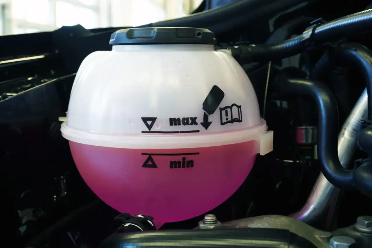Dep&oacute;sito de expansi&oacute;n con l&iacute;quido refrigerante rosa. Indica niveles m&iacute;nimo y m&aacute;ximo. Es hora de rellenar l&iacute;quido refrigerante si est&aacute; bajo.