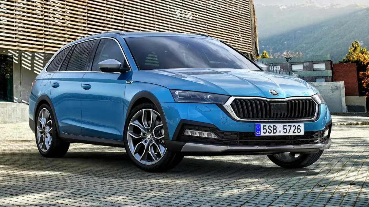 Un coche azul con matr&iacute;cula 5SB 5726, posiblemente un modelo familiar tipo SUV, aparcado frente a un edificio moderno.