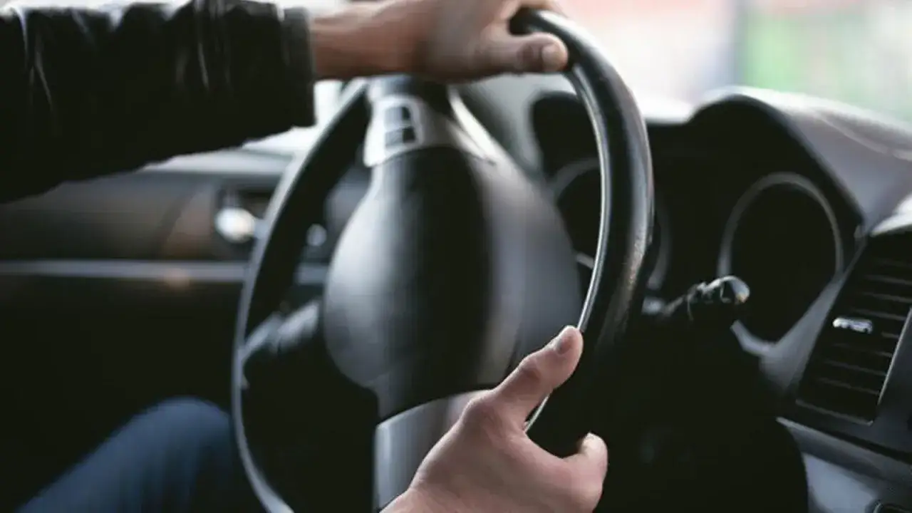 Manos sujetando el volante de un coche, sintiendo el chirrido al girar el volante.