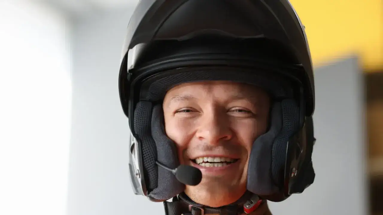 Hombre sonriente con casco de moto negro, listo para conducir su ciclomotor con permiso B.