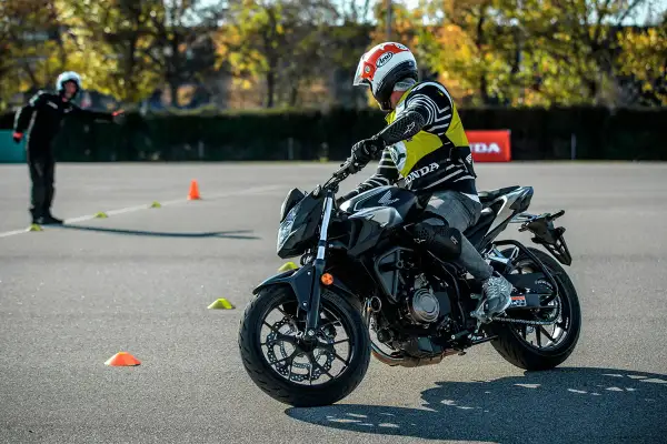 Persona con casco y chaleco amarillo practica en moto en circuito con conos. ¡Así me puedo sacar el carnet A directamente!