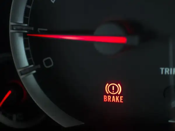 El panel de un coche muestra una luz de advertencia roja con un signo de exclamación dentro de un círculo y la palabra "BRAKE". Esto indica que algo no va bien con el sistema de frenos.