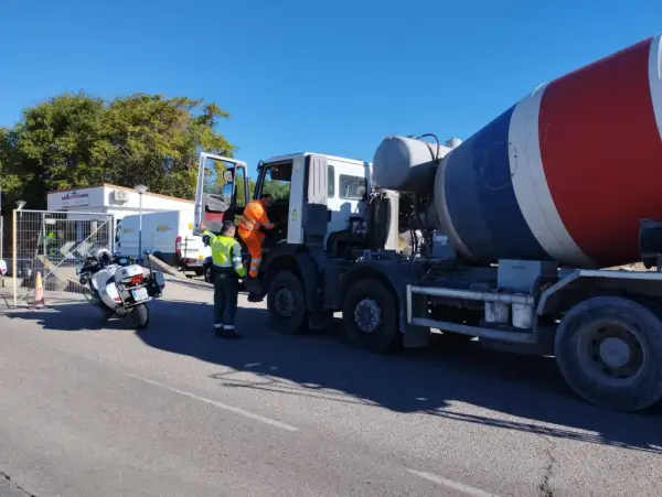 Agente de tráfico supervisa camión hormigonera en una estación de pesaje. La **itv en carretera** es crucial para la seguridad vial.