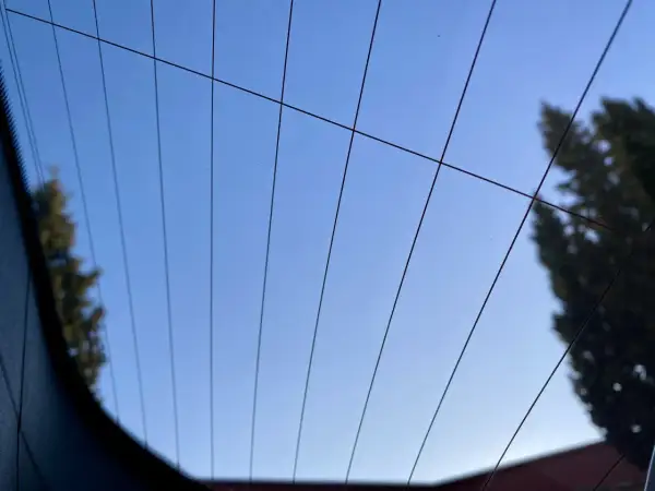 Líneas finas cruzan el cielo azul claro, reflejando la luneta térmica de un coche.