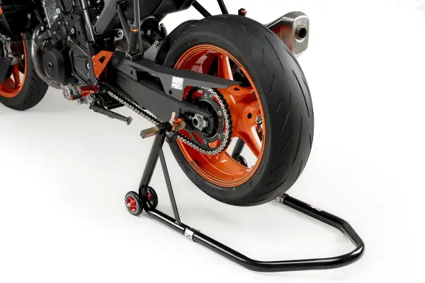 La rueda trasera de una moto deportiva naranja está elevada sobre un caballete basculante negro.