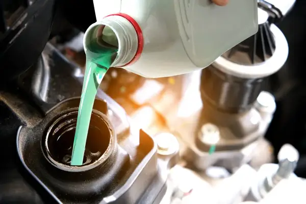 Vertiendo aceite 2T verde brillante en el motor de una motocicleta. El correcto porcentaje aceite 2t es crucial para el rendimiento.