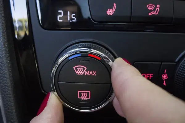Dedo girando el dial para desempañar cristales coche. Muestra la temperatura 21.5 y el icono de desempañado.